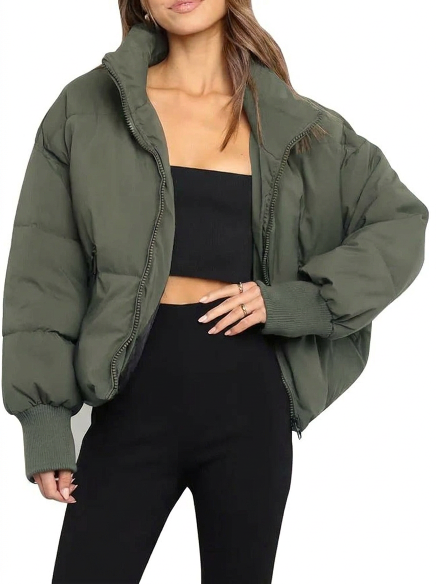 Olive green cropped puffer jacket with quilted padding, high collar, zip front, and ribbed cuffs worn over black layers.