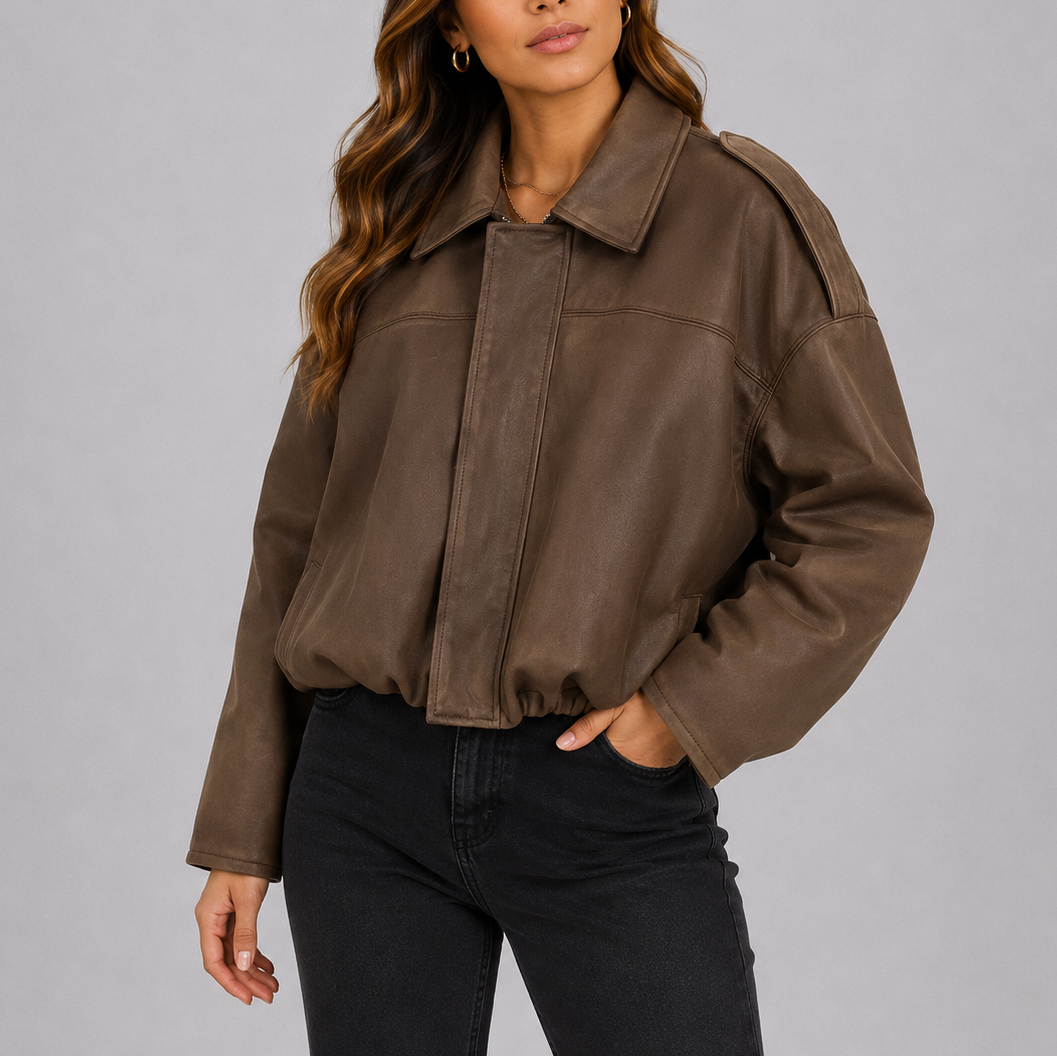 A woman wearing a cropped brown suede bomber jacket with an oversized fit and wide sleeves
