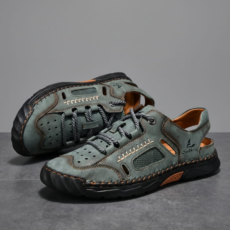 Pair of green nubuck leather fisherman sandals stacked on a gray studio backdrop