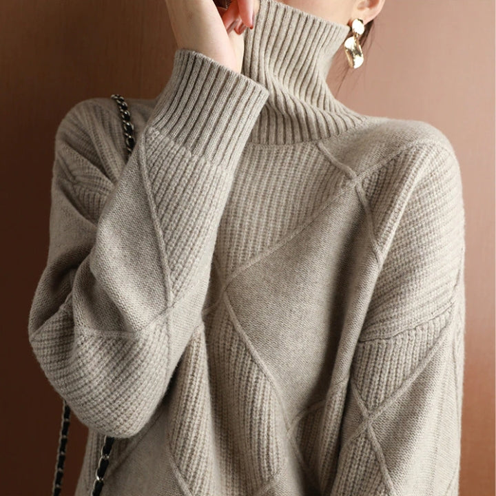 Woman wearing a light gray textured turtleneck sweater featuring a relaxed fit and ribbed cuffs.