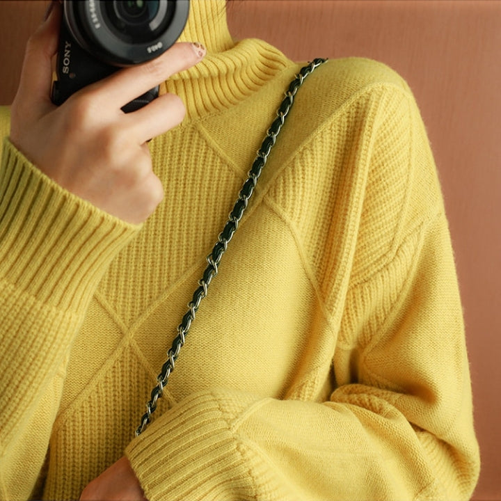 Close-up of the mustard yellow ribbed turtleneck sweater highlighting the textured knit fabric and shoulder detail.