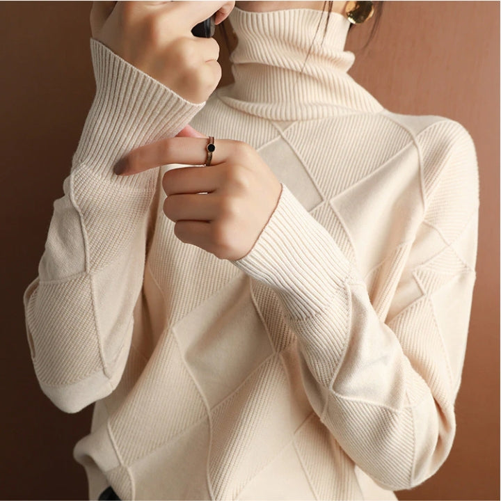 Woman wearing a cream ribbed turtleneck knit sweater with a textured geometric pattern and long sleeves.
