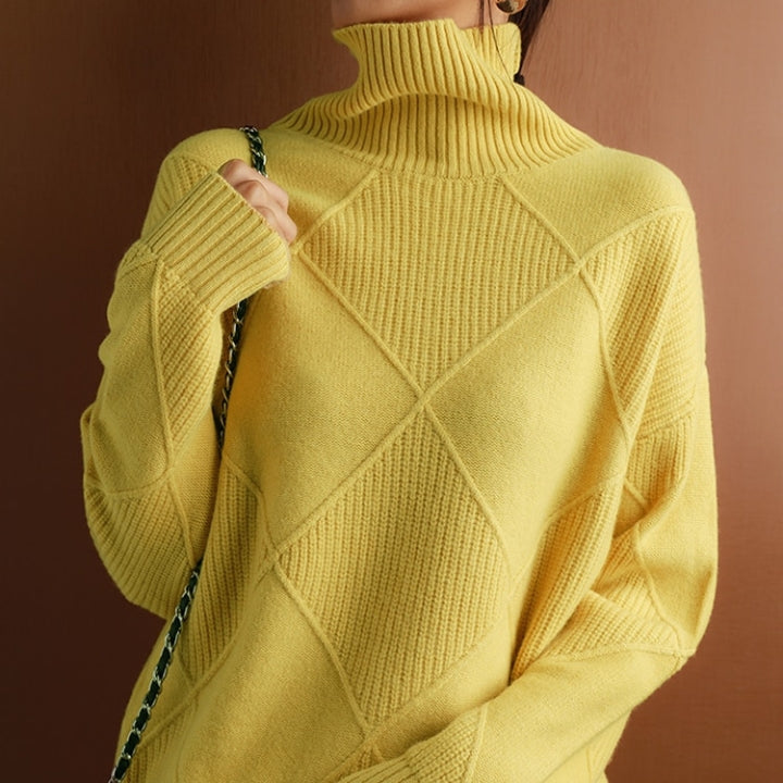 Woman wearing a mustard yellow ribbed turtleneck knit sweater with long sleeves, textured geometric knit pattern, and a relaxed fit.