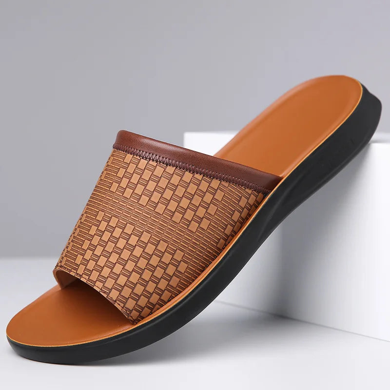 Tan woven-texture leather slide sandal with a dark brown trim strap and matching molded footbed, angled on a white display block.
