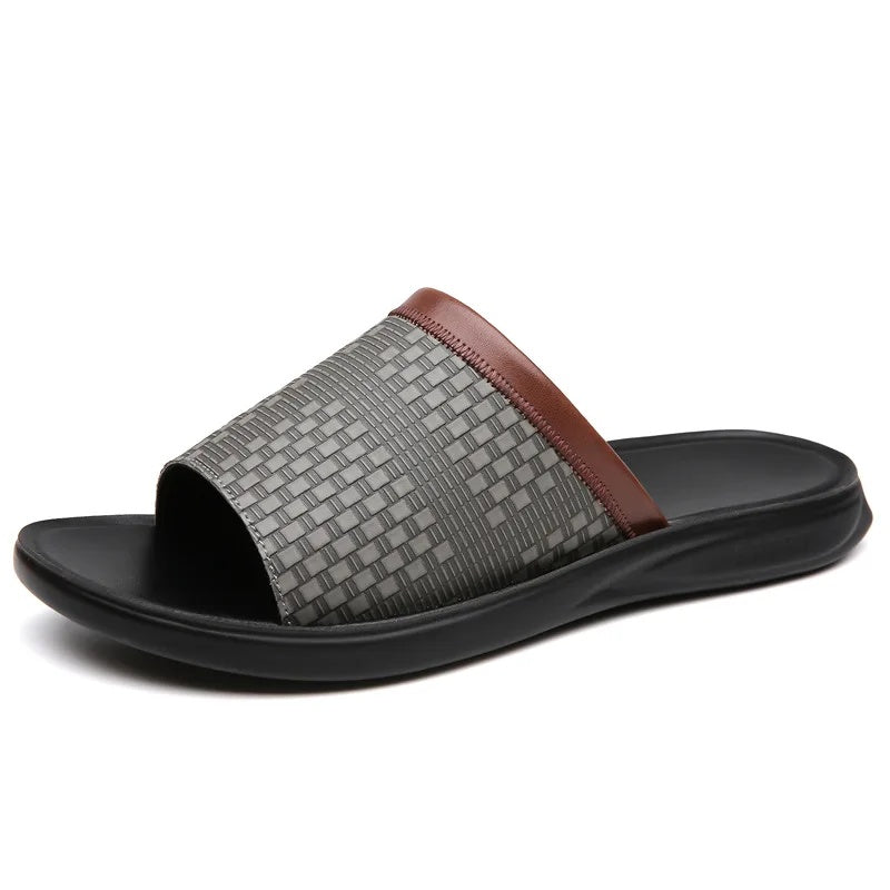 Side profile product shot of a gray woven-texture leather slide sandal on a plain white background, showing the brown trim strap and black molded sole.