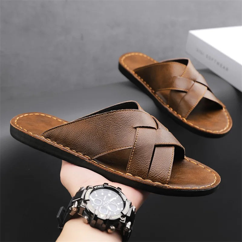 Pair of brown woven leather cross-strap sandals balanced on a person's wrist wearing a watch, styled as a lifestyle product shot.