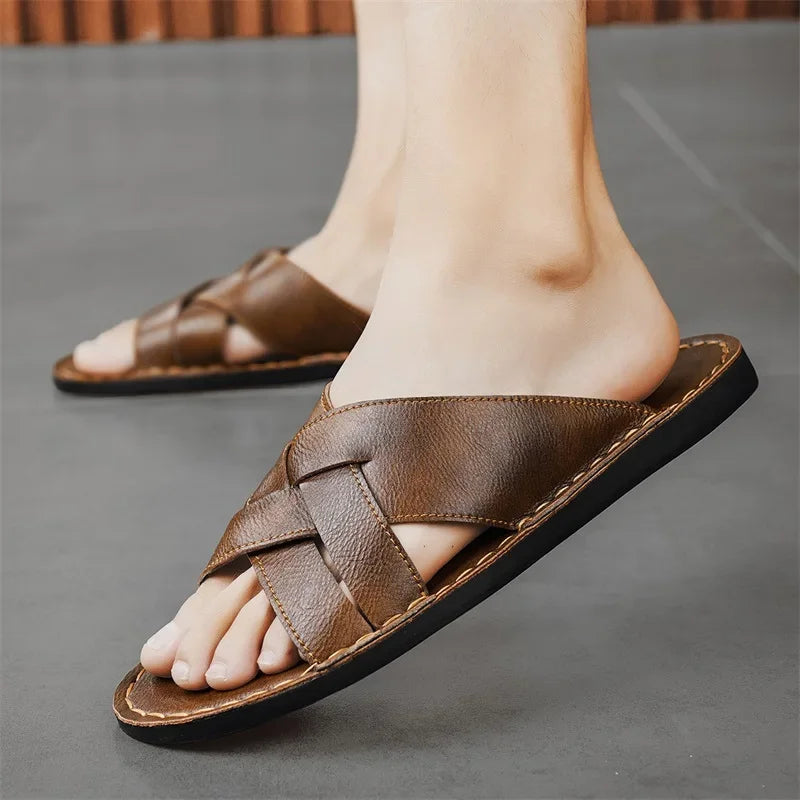 Close-up of a model's foot wearing a brown woven leather cross-strap sandal while walking outdoors.