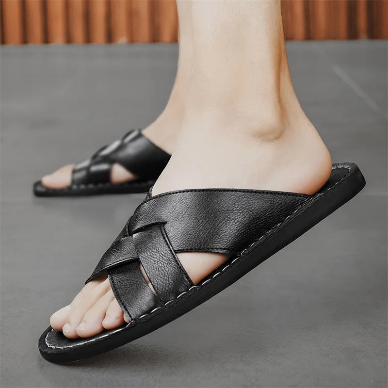 Close-up of a model's foot wearing a black woven leather cross-strap sandal while walking outdoors.