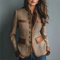 Woman wearing a taupe tweed blazer with contrasting brown trim, button-front closure, patch pockets, long sleeves, and tailored silhouette.