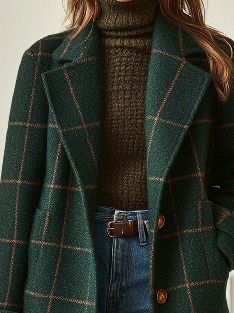 Close-up of a woman wearing a dark green plaid long coat over a brown turtleneck sweater, showing the notched lapel and button-front design.