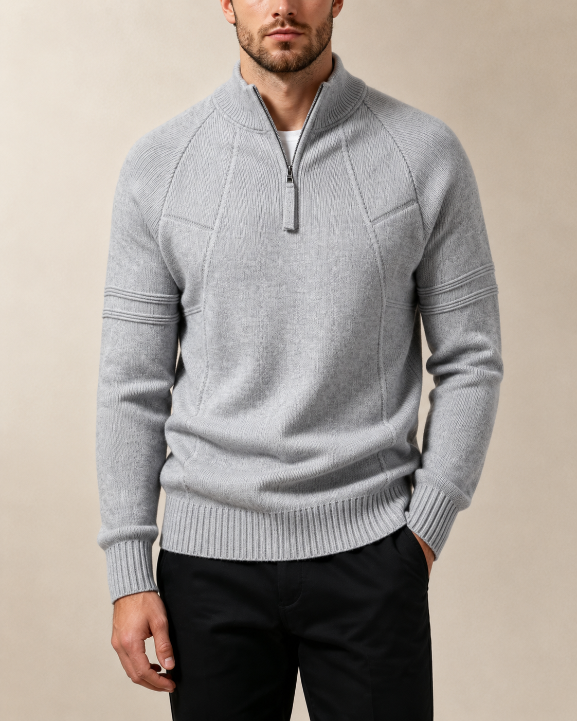 Gray fitted knit quarter-zip sweater with raglan sleeves, raised chest seams, and ribbed cuffs worn with black trousers.