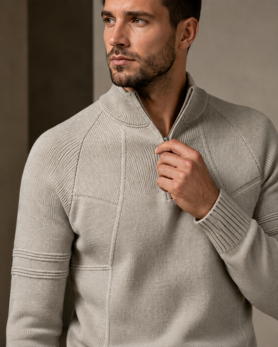 Beige fitted knit quarter-zip sweater with raglan sleeves, raised seamed panels, and a high ribbed mock neck collar. 