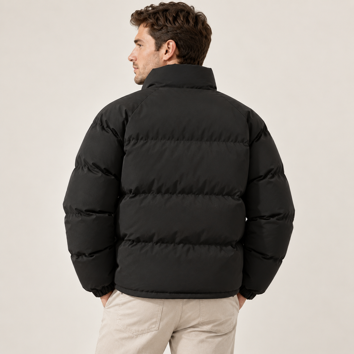 A man wearing a black fleece-lined puffer jacket with a high collar, shown from the back