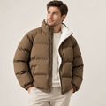 A man wearing a brown fleece-lined puffer jacket with a high collar and cotton-blend shell