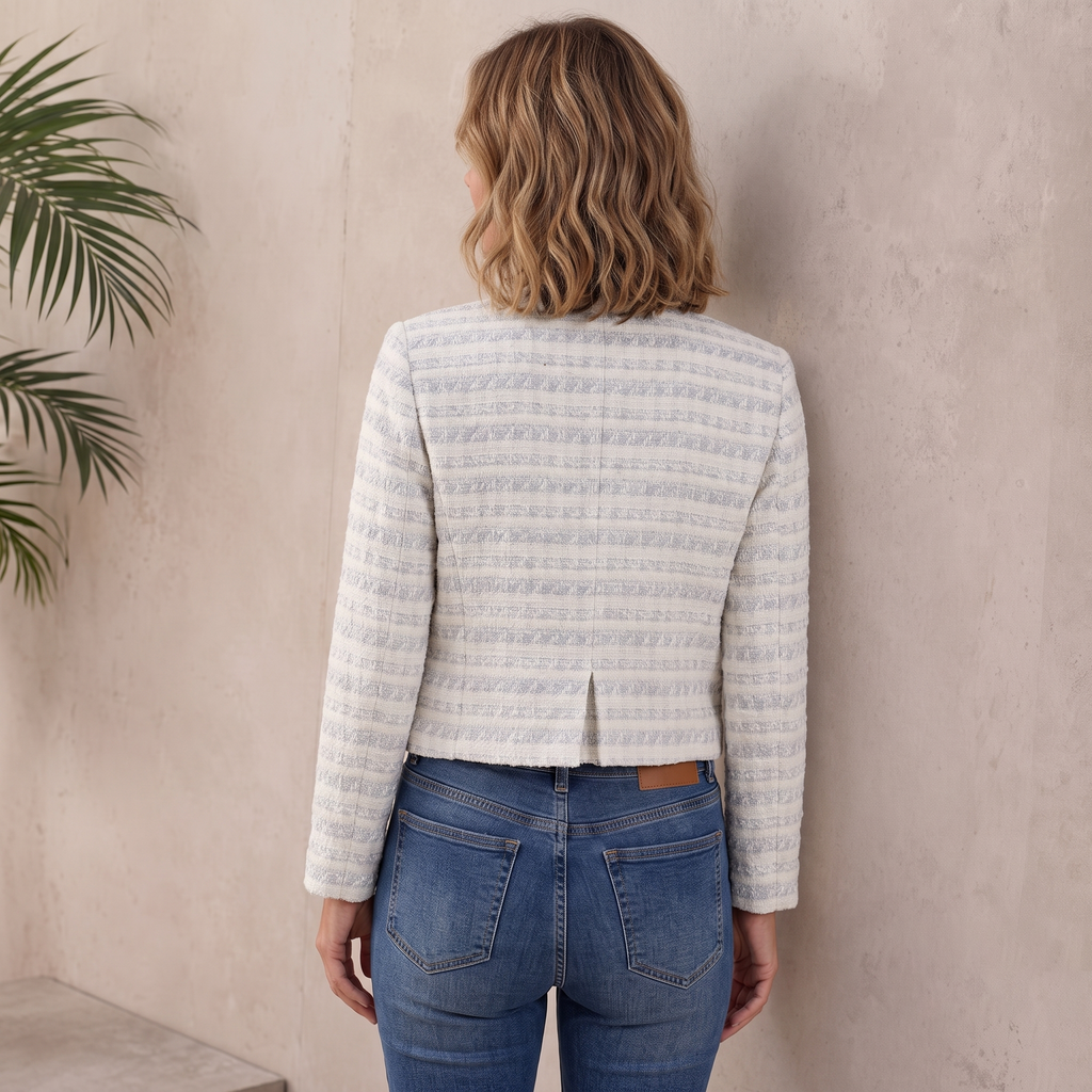 Back view of a woman wearing a light gray textured tweed jacket with a fitted silhouette and long sleeves.