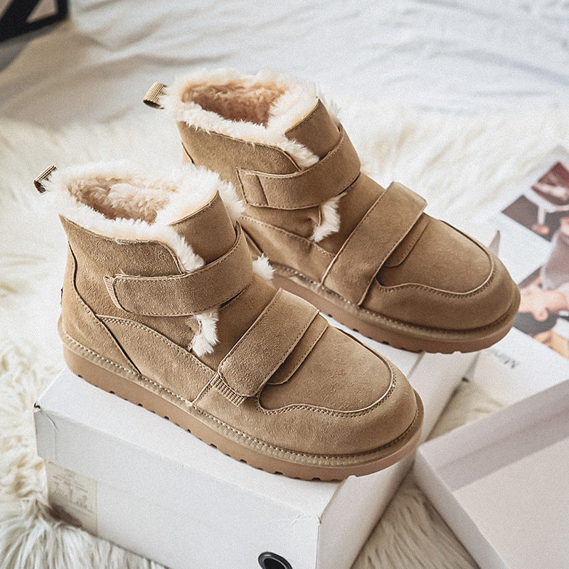 Pair of tan suede fleece-lined winter boots resting on their shoe box, on a faux fur rug.