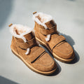 Pair of tan suede winter boots with fleece lining and velcro strap closures, on a light gray background.