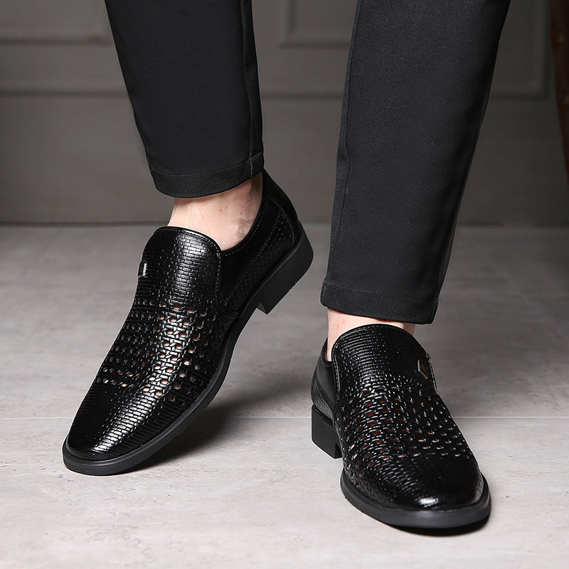 Black woven calfskin leather slip-on loafers with breathable perforated detailing and flexible black soles, worn with black trousers indoors.