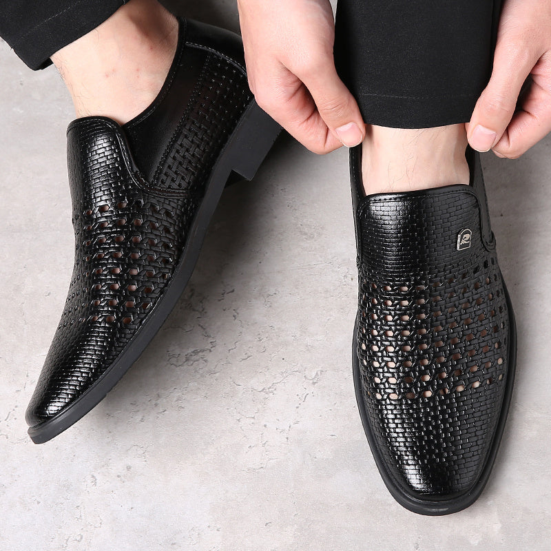 Black woven calfskin leather loafers with breathable perforated upper and flexible black outsole, being slipped on with black trousers.