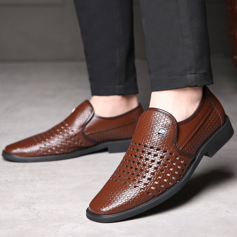 Brown woven calfskin leather loafers with breathable perforated detailing and a flexible black sole, worn with black trousers in a modern indoor setting.