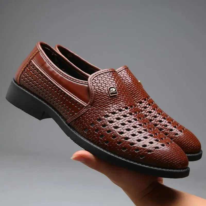 Brown woven calfskin leather loafers with breathable perforations and flexible black outsoles, held in one hand against a gray background.