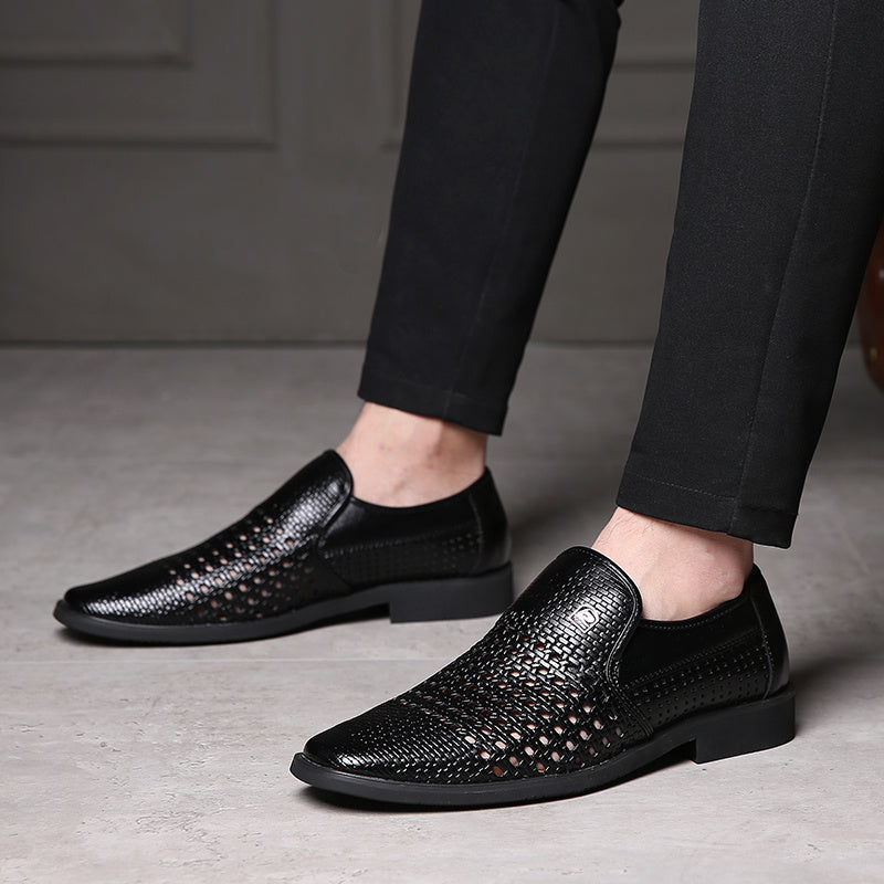 Black woven calfskin leather loafers with breathable perforated upper, slip-on design, and flexible black sole, styled with black trousers in a modern indoor setting.