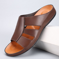 Dark brown leather slip-on sandal with cutout strap detailing and an orange-toned footbed, angled on a white display block.