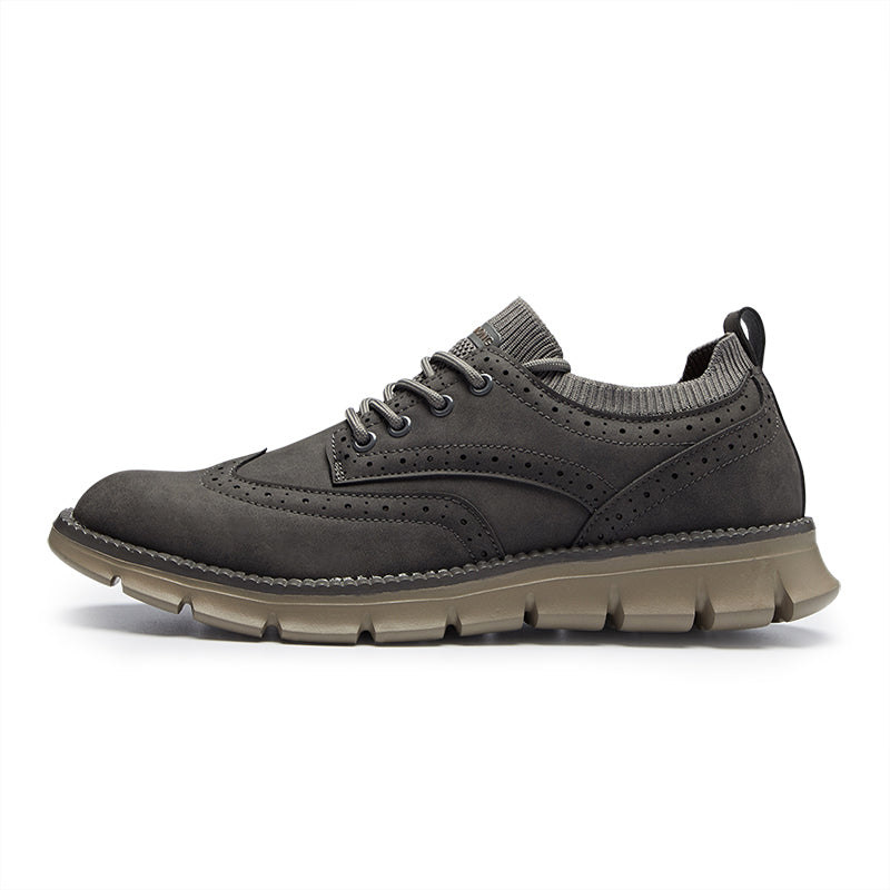 Side profile of a single gray suede brogue-style sneaker on a plain white background.