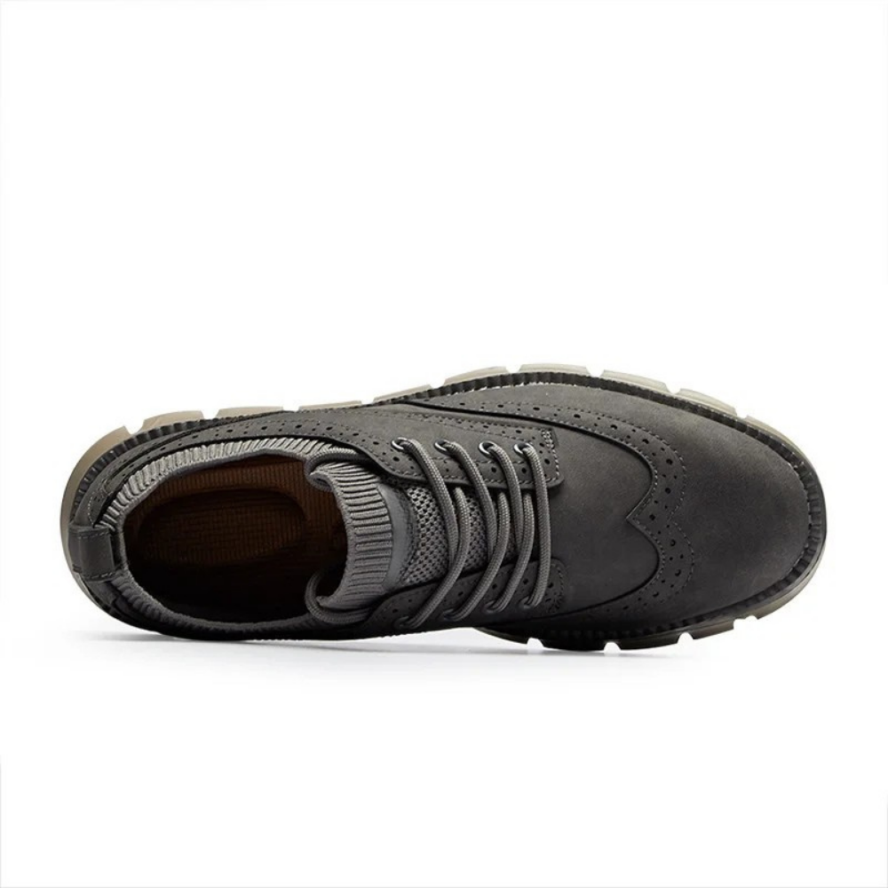 Overhead view of a single gray suede brogue-style sneaker showing the laces and interior, on a plain white background.