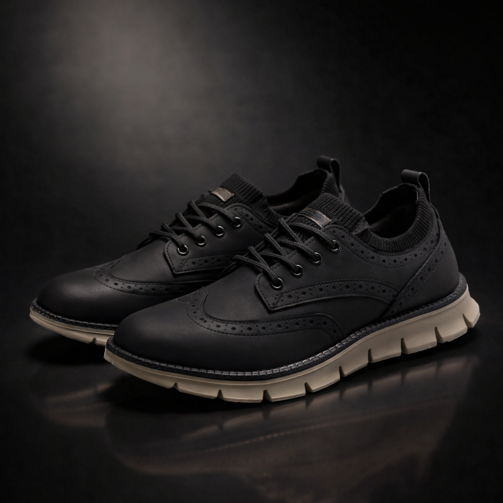 Pair of black brogue-style sneakers on a reflective surface against a dark moody studio background.