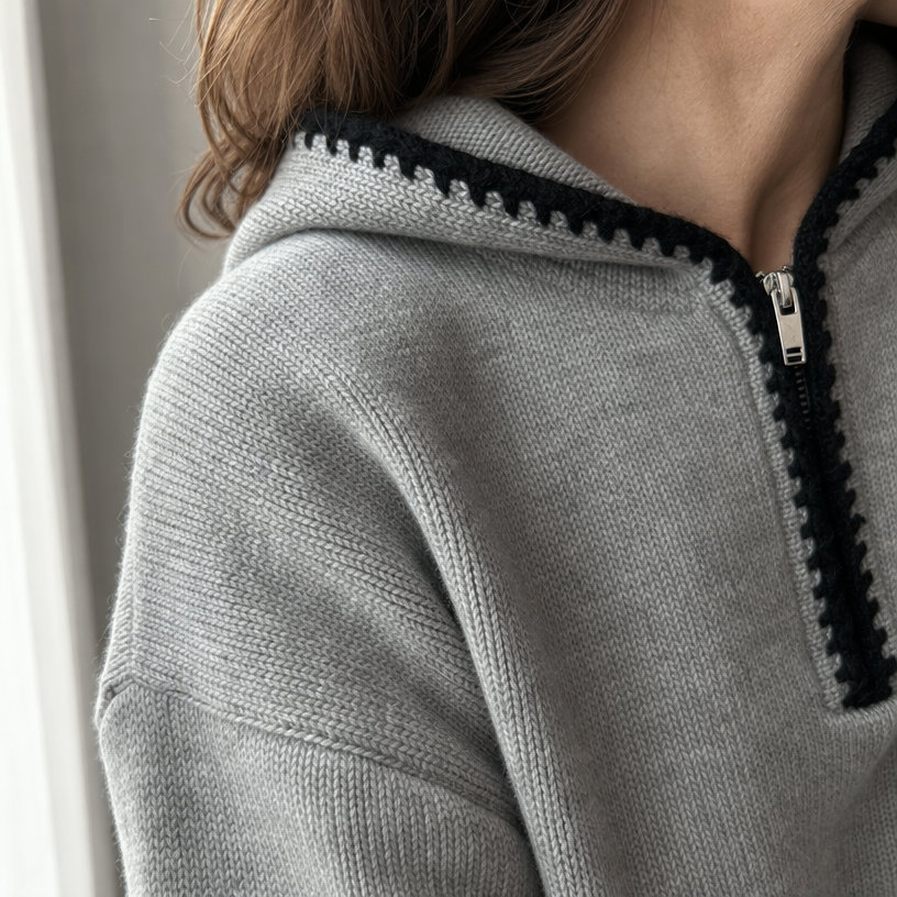 Close-up of gray knit pullover showing the hood, half-zip, and contrast trim