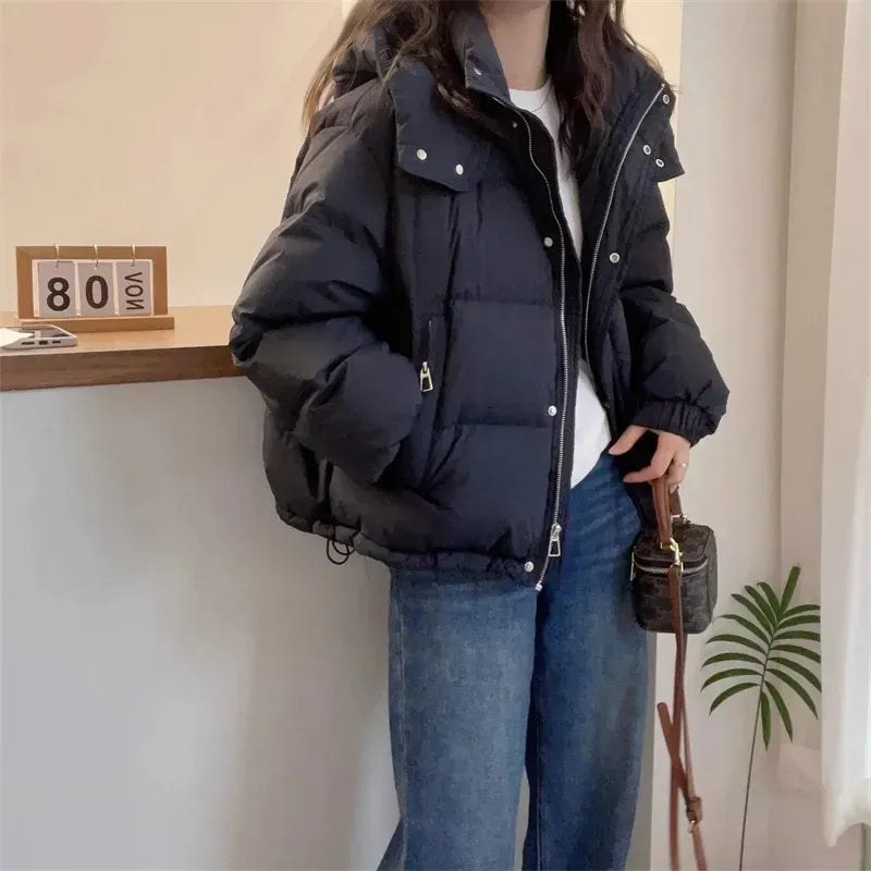 Black quilted puffer jacket with a high funnel neck, attached hood, and full zip closure in a relaxed layering fit.