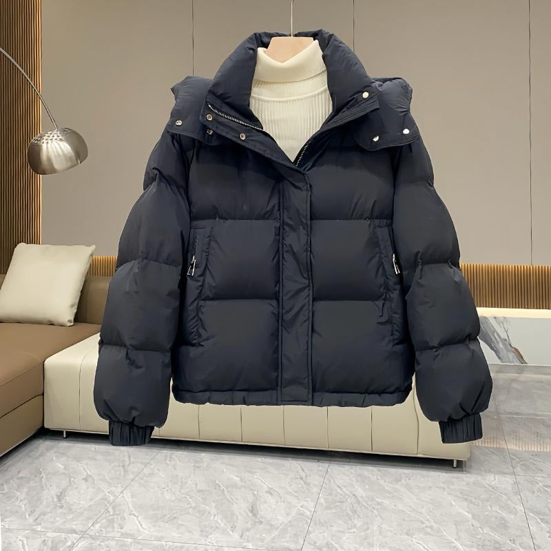 Black hooded puffer jacket with quilted insulation, high funnel neck, and relaxed fit, displayed on a hanger.