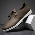 Brown leather lace-up sneaker with white sole propped diagonally against a white geometric block in a studio setting