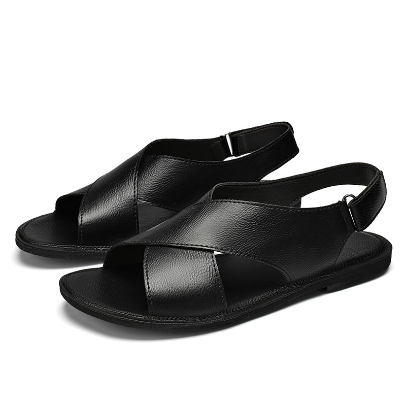 Pair of black leather cross-wrap sandals arranged together on a white background, showing the crisscross straps and buckle closures on both shoes.