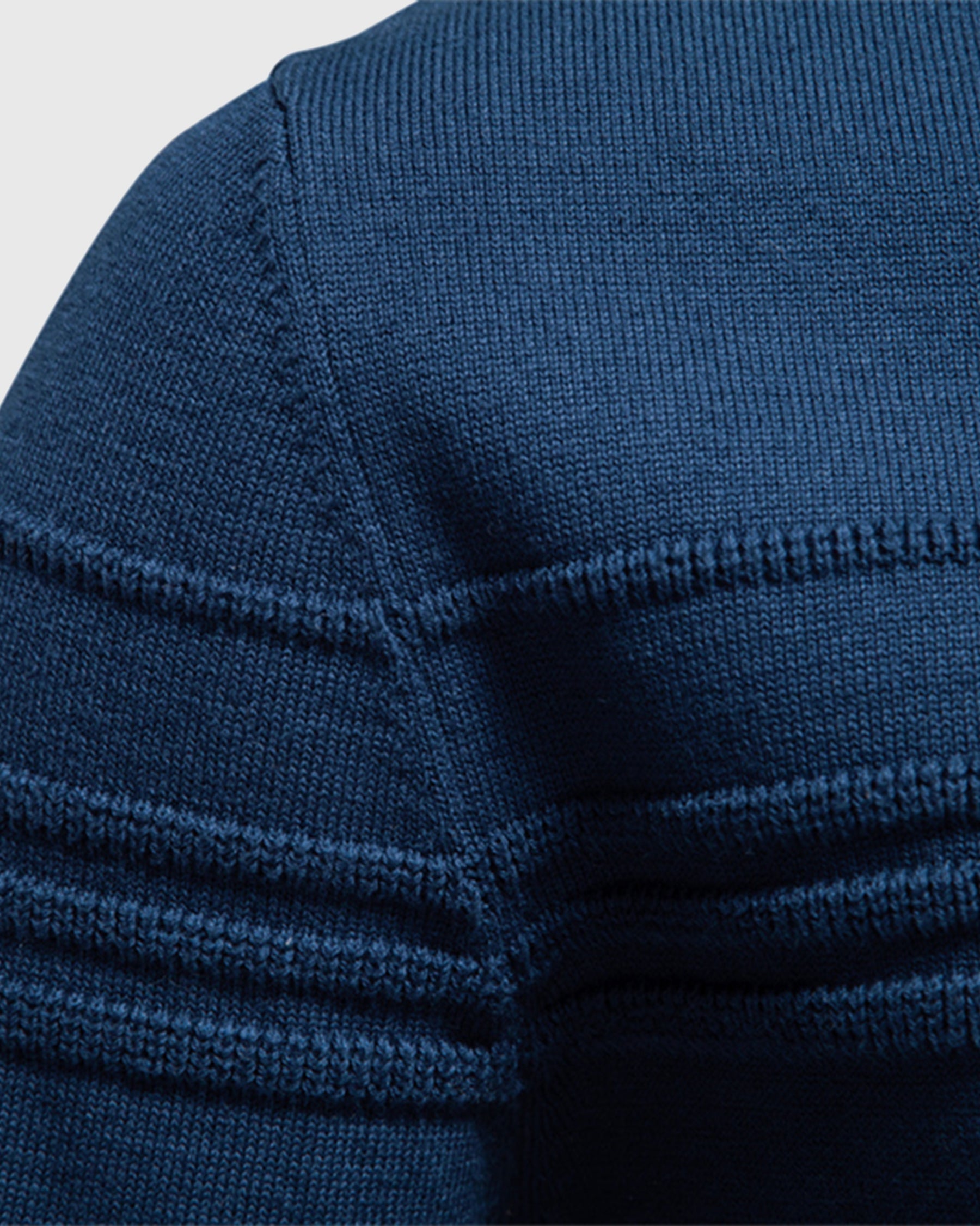Close-up of the blue crew neck sweater highlighting the textured shoulder knit and ribbed sleeve design.