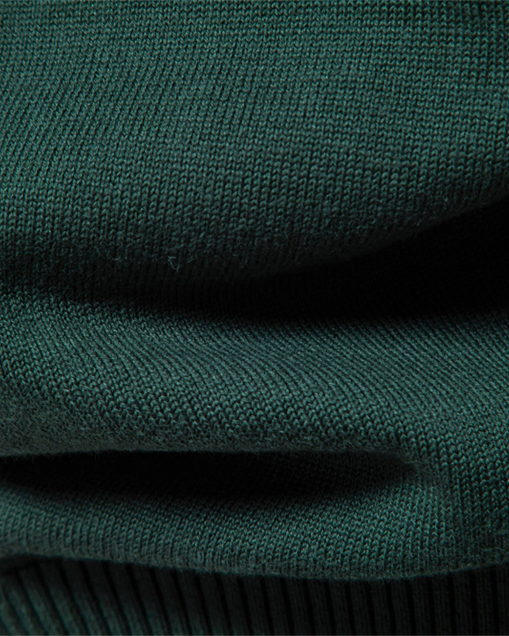 Close-up of forest green ribbed knit sweater texture and side seam