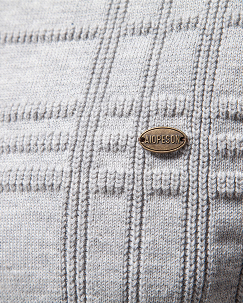 Close-up of brown leather brand patch on light grey knit sweater