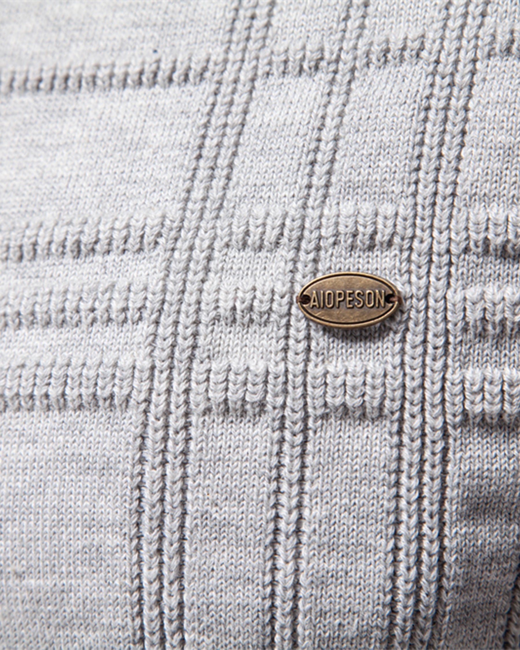Close-up of brown leather brand patch on light grey knit sweater