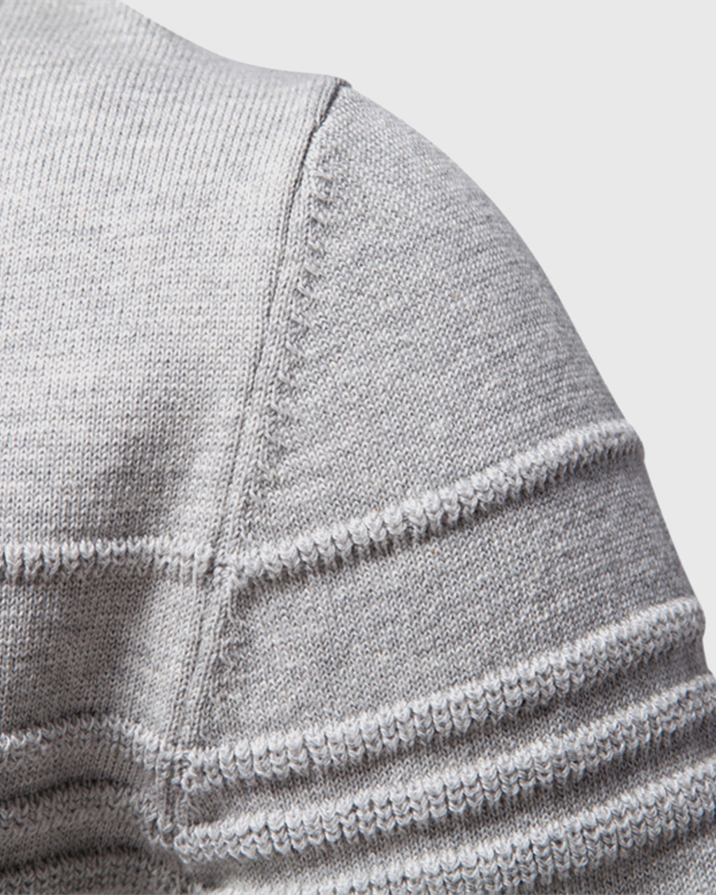 Close-up of light grey knit sweater shoulder seam detail