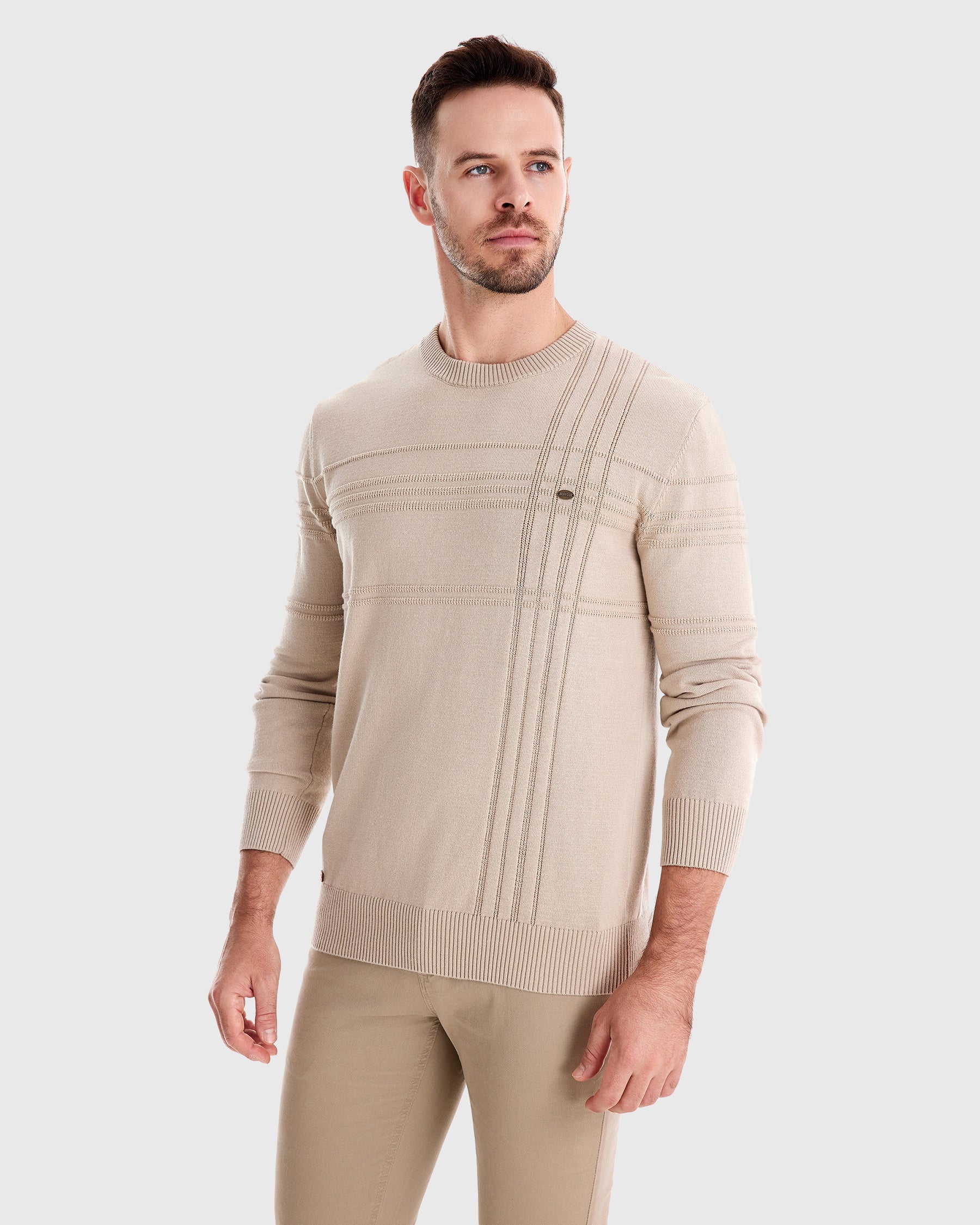 Man wearing beige knit sweater and matching trousers, three-quarter view