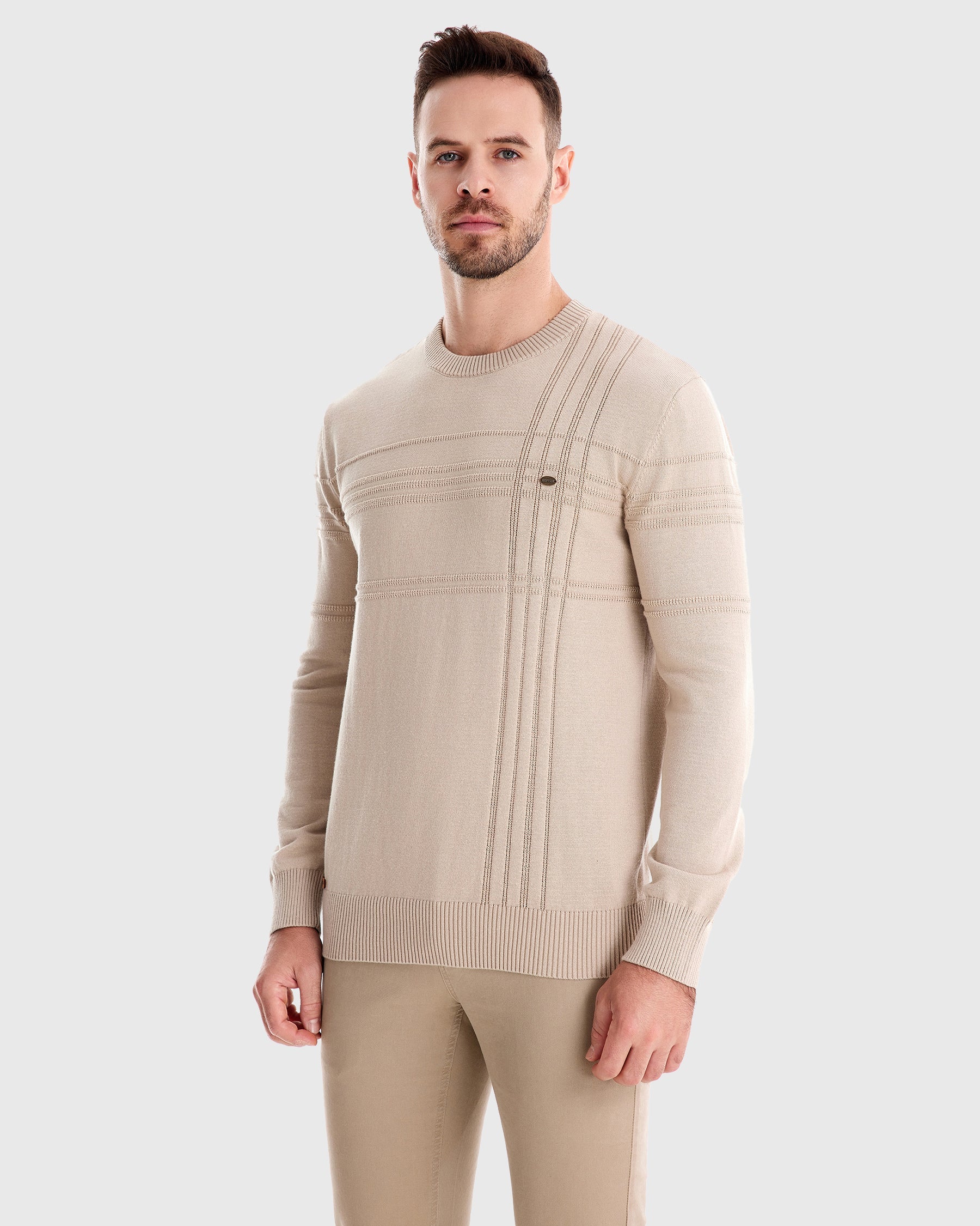 Man wearing beige textured knit sweater and trousers, full-body front view