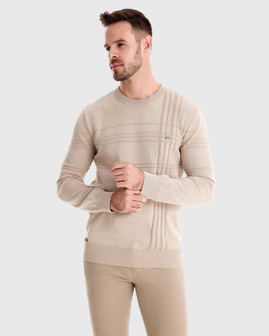 Man wearing beige textured knit sweater and trousers, full-body angled view
