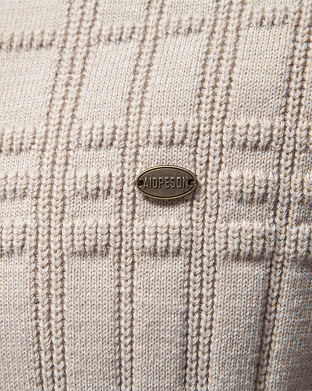 Close-up of beige knit sweater textured grid pattern with woven button detail