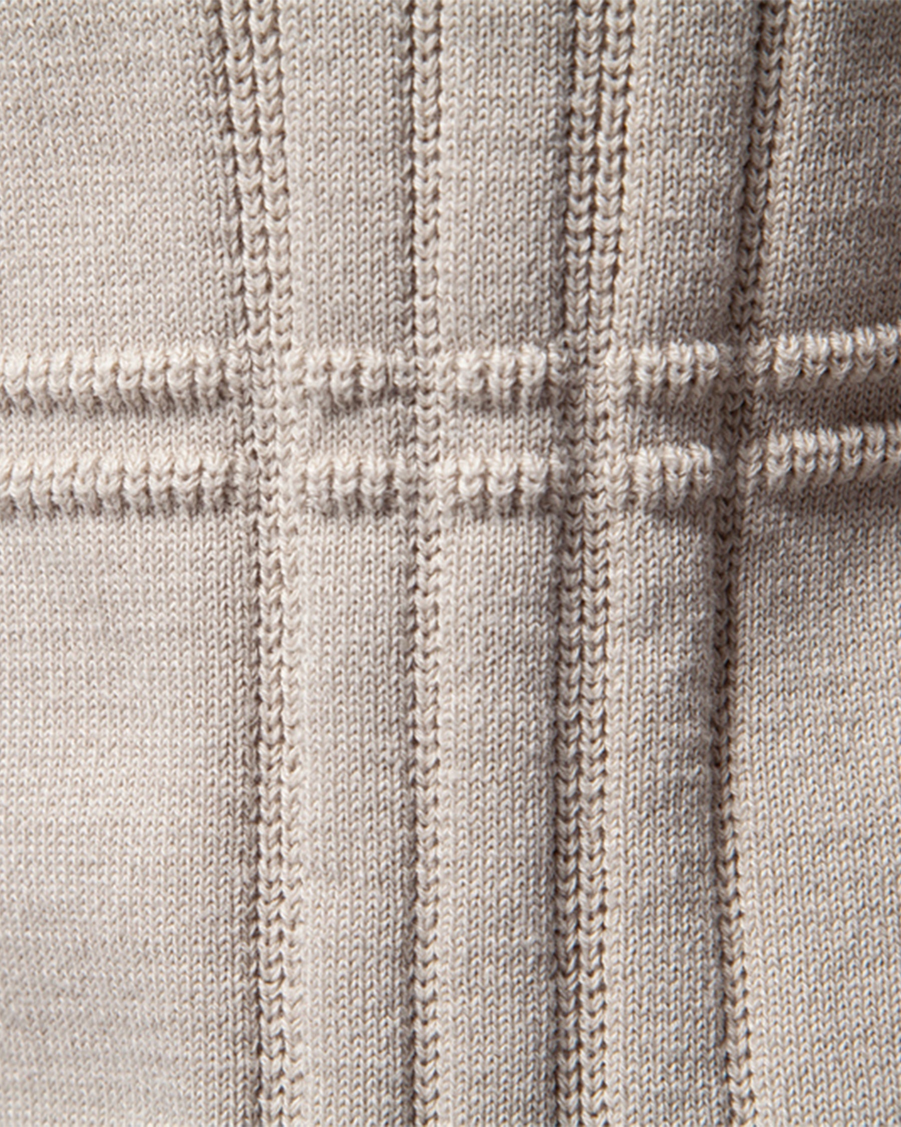 Close-up of beige knit sweater vertical ribbed texture