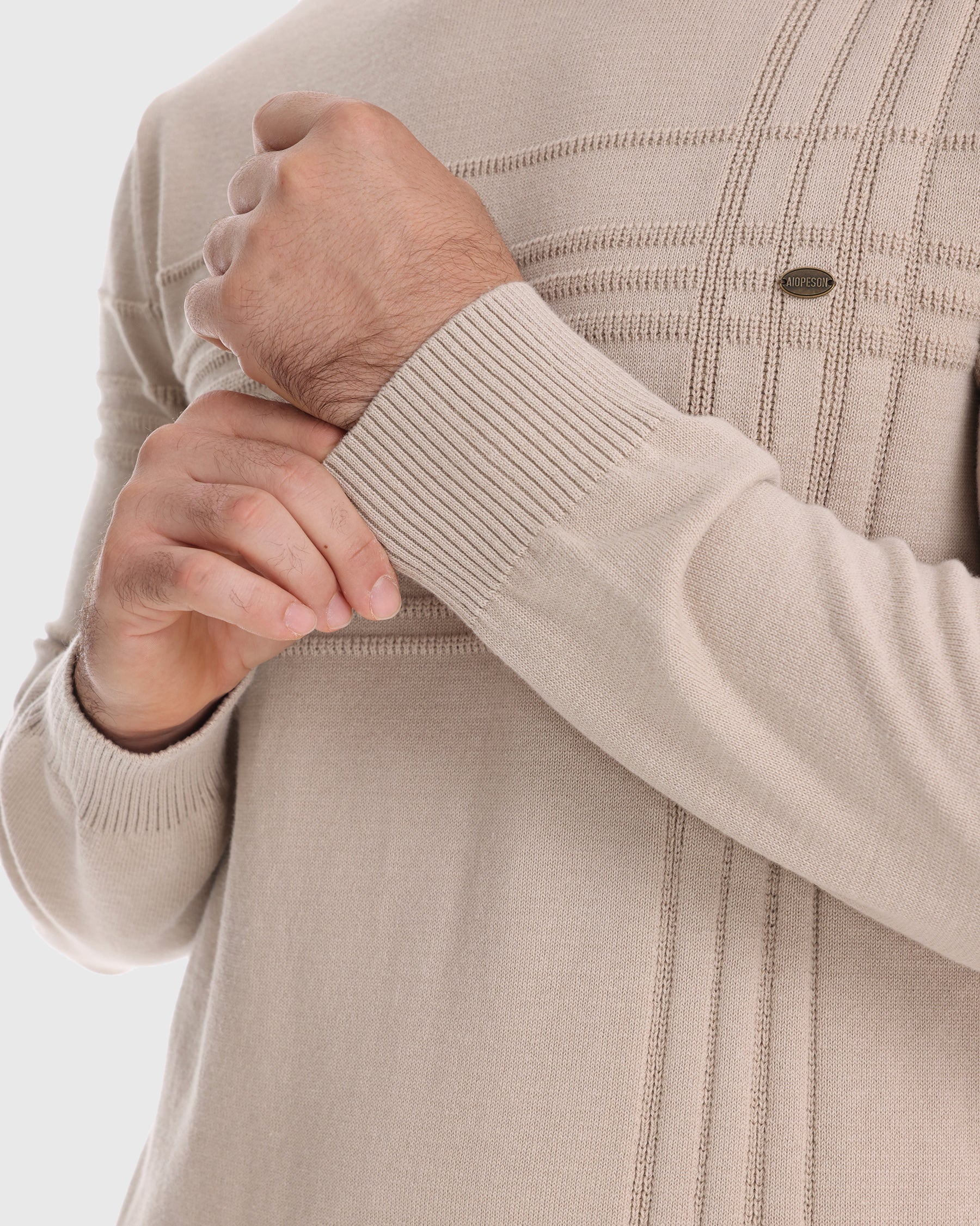 Close-up of man's hand resting on beige knit sweater sleeve