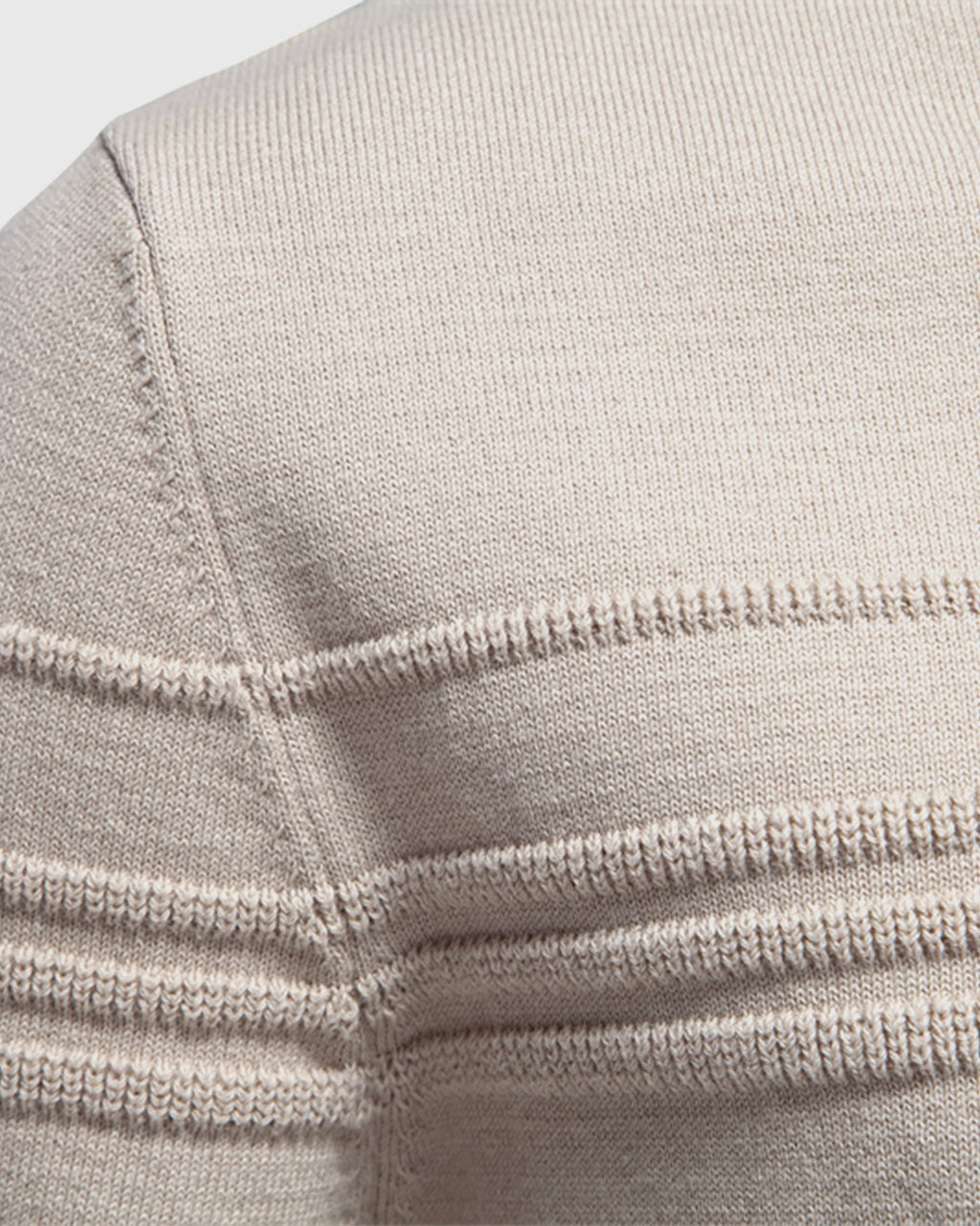 Close-up of beige knit sweater shoulder seam and collar detail