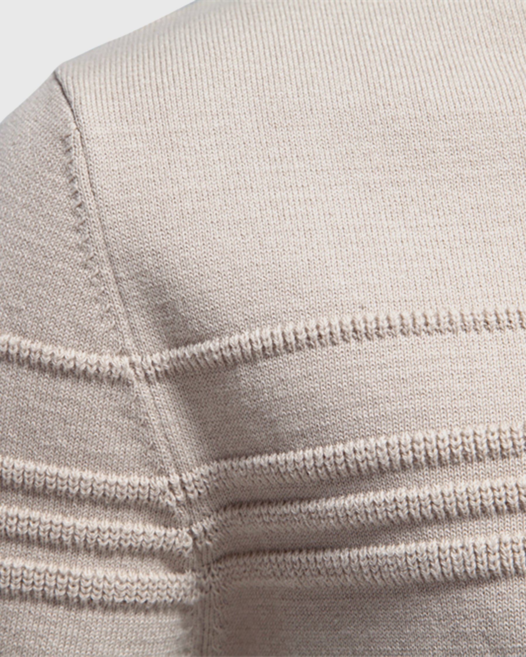 Close-up of beige knit sweater shoulder seam and collar detail