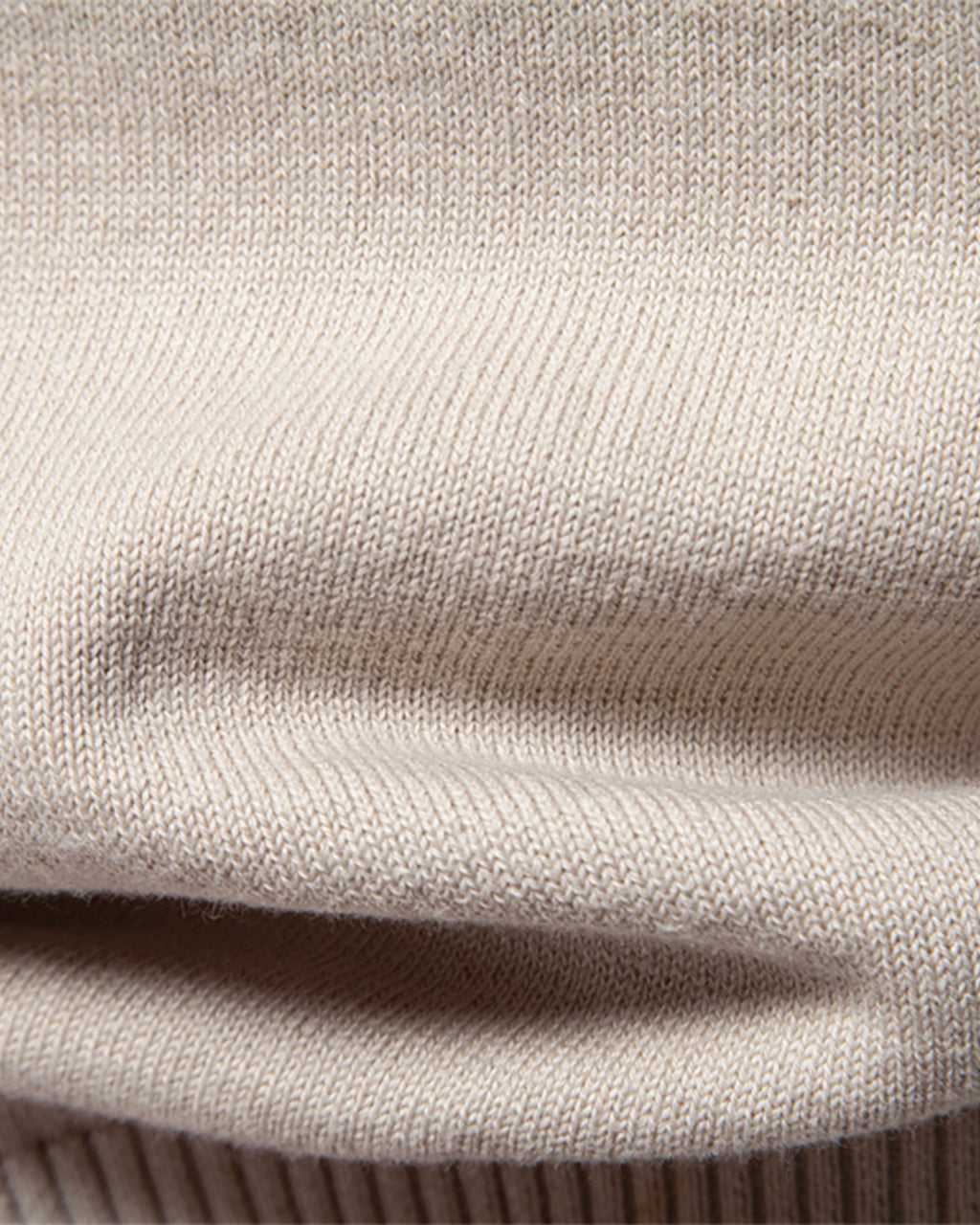 Close-up of beige knit sweater folded fabric texture