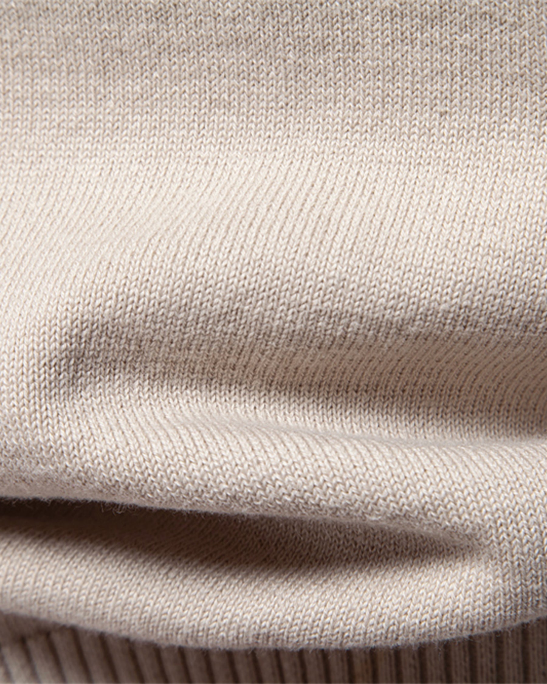 Close-up of beige knit sweater folded fabric texture